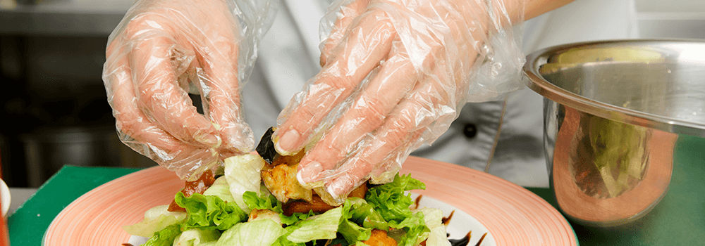 Hands with gloves on making a salad