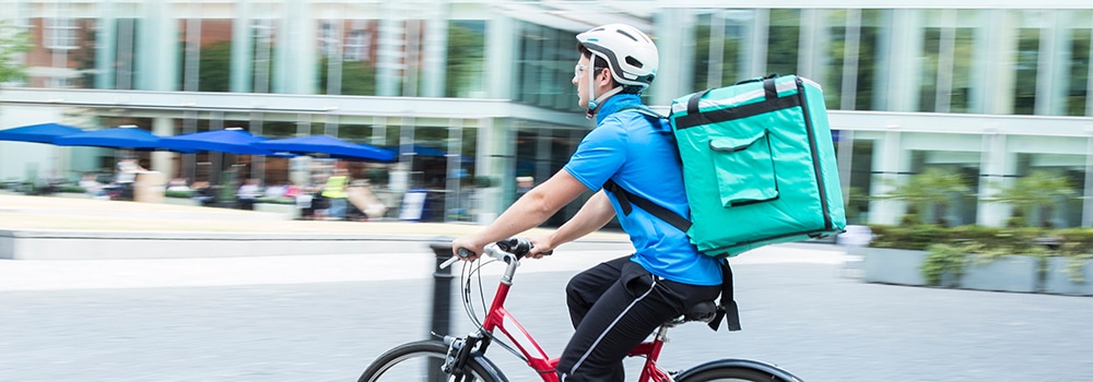 Deliveryperson with food backpack on bicycle