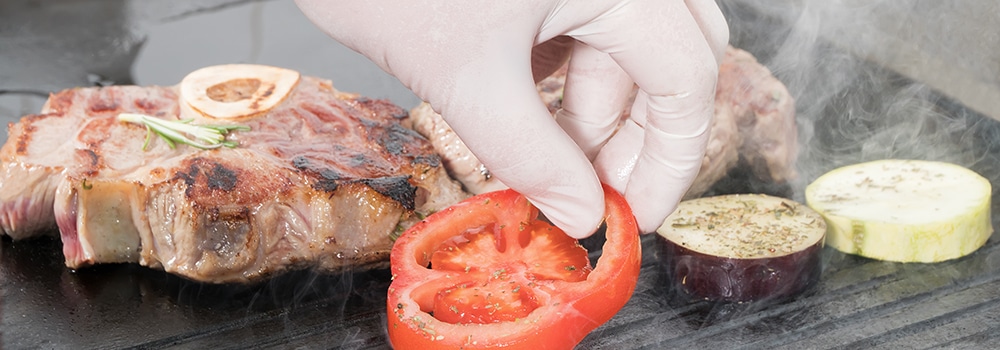 Hand placing food on hot grill