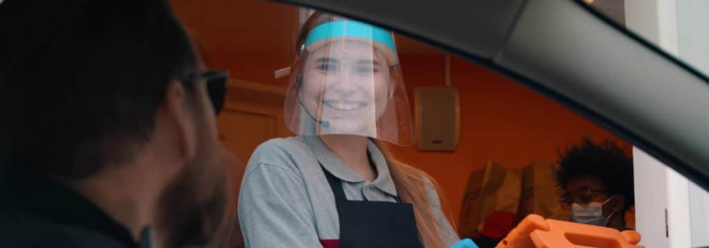 young woman at drive thru with face shield on
